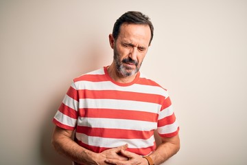 Middle age hoary man wearing casual striped t-shirt standing over isolated white background with hand on stomach because indigestion, painful illness feeling unwell. Ache concept.