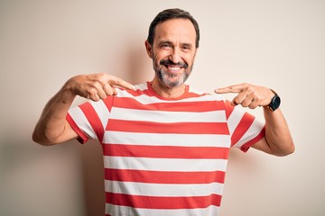 Middle age hoary man wearing casual striped t-shirt standing over isolated white background looking confident with smile on face, pointing oneself with fingers proud and happy.