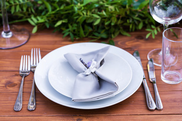 Beautifully decorated wooden table in a summer open-air cafe. Green branch and fresh flowers table decoration