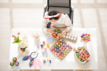 Easter, holiday concept - top view of young women coloring eggs for easter