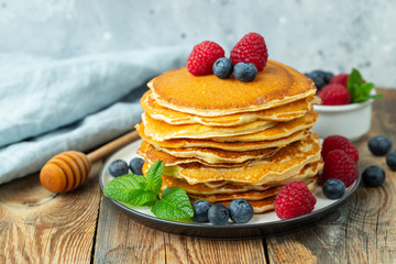 Close-up delicious pancakes, with fresh blueberries, raspberry's and honey on a light background