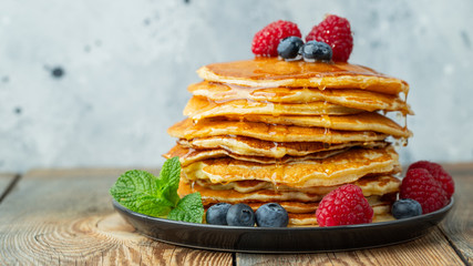 Close-up delicious pancakes, with fresh blueberries, raspberry's and honey on a light background. With copy space