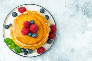 Close-up delicious pancakes, with fresh blueberries, raspberry's and honey on a light background. Top view with copy space