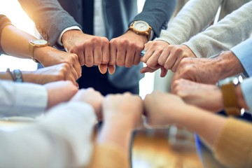 Group of business workers standing bumping fists at the office