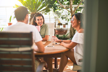 Beautiful family sitting on terrace drinking cup of coffee speaking and smiling