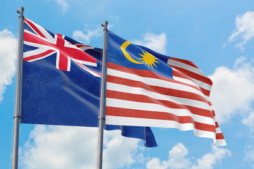 Malaysia and Anguilla flags waving in the wind against white cloudy blue sky together. Diplomacy concept, international relations.