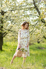 A gorgeous girl walks in a flowering spring garden. The concept of unity of man with nature