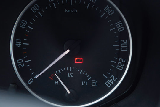 Close up shot of a car dashboard with the battery icon lit.