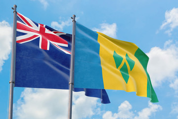 Saint Vincent And The Grenadines and Anguilla flags waving in the wind against white cloudy blue sky together. Diplomacy concept, international relations.