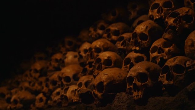 This spooky panning video shows a massive pile of skulls bones in a dark room.