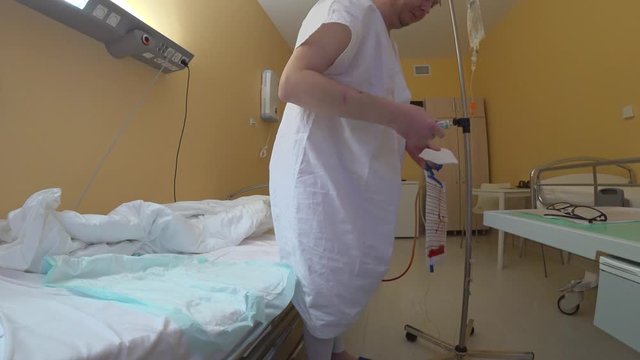 The patient makes an application with a smear bandage to the area below the back. Crumpled bed with disposable diaper, hospital clothes, sterile gauze dressing tube with vague ointment.