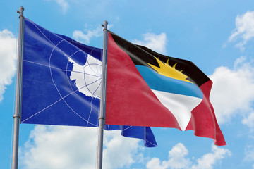 Antigua and Barbuda and Antarctica flags waving in the wind against white cloudy blue sky together. Diplomacy concept, international relations.