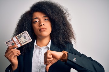 Young african american business woman with afro hair holding a bunch of cash dollars banknotes with...