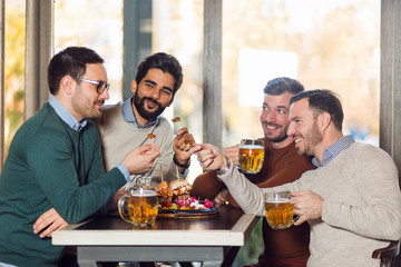 Group of happy friends drinking beer at pub