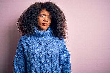 Young beautiful african american woman with afro hair wearing winter sweater over pink background skeptic and nervous, frowning upset because of problem. Negative person.