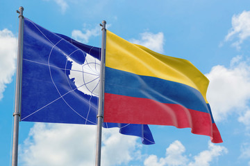 Colombia and Antarctica flags waving in the wind against white cloudy blue sky together. Diplomacy concept, international relations.