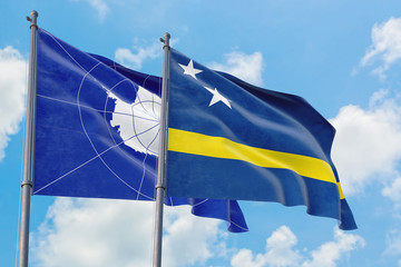 Curacao and Antarctica flags waving in the wind against white cloudy blue sky together. Diplomacy concept, international relations.