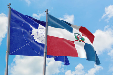Dominican Republic and Antarctica flags waving in the wind against white cloudy blue sky together....