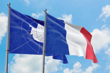 France and Antarctica flags waving in the wind against white cloudy blue sky together. Diplomacy concept, international relations.