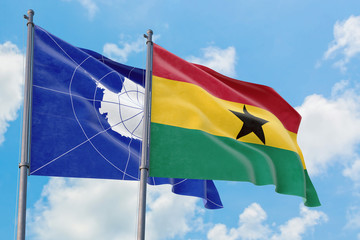 Ghana and Antarctica flags waving in the wind against white cloudy blue sky together. Diplomacy concept, international relations.