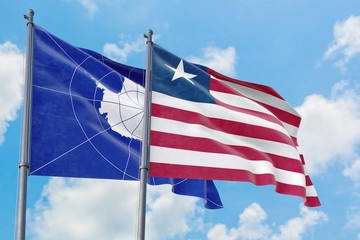 Liberia and Antarctica flags waving in the wind against white cloudy blue sky together. Diplomacy...