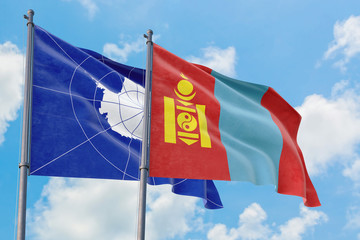 Mongolia and Antarctica flags waving in the wind against white cloudy blue sky together. Diplomacy concept, international relations.