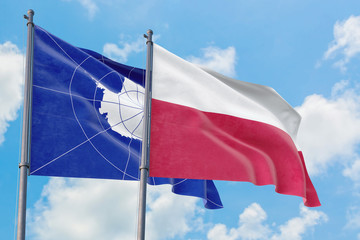 Poland and Antarctica flags waving in the wind against white cloudy blue sky together. Diplomacy concept, international relations.