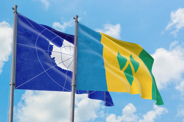 Saint Vincent And The Grenadines and Antarctica flags waving in the wind against white cloudy blue...
