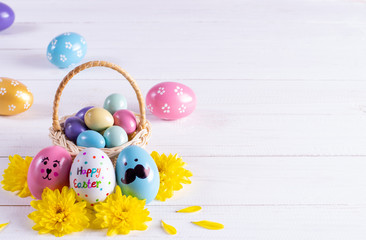 Easter basket filled with colorful eggs on white wooden background. Copy space.