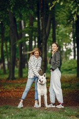 Fototapeta premium Beautiful girl in a white blouse. Women in a summer forest. Ladies with a dog