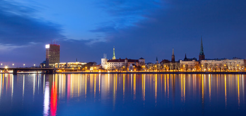 Fototapeta na wymiar Panorama of Old Riga in Latvia, Europe, view of Presidential Castle, promenade with city lights reflecting over the river of Daugava, night view, twilight, banner