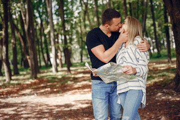 Fototapeta premium Tourists in a summer forest. Couple with a map.