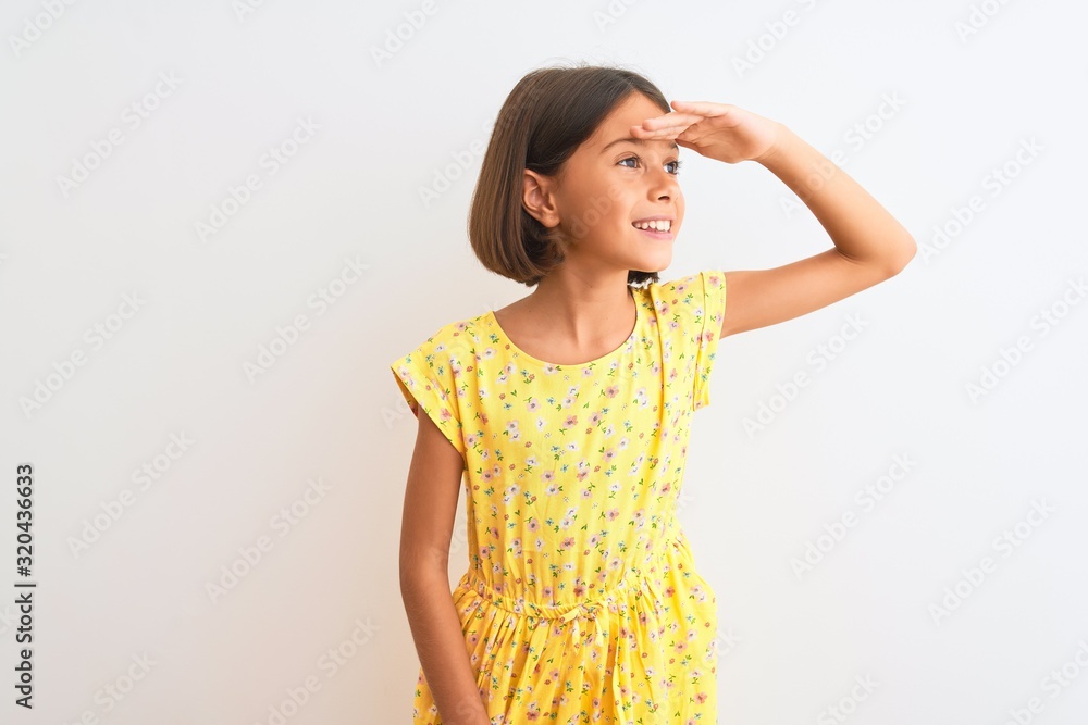 Wall mural young beautiful child girl wearing yellow floral dress standing over isolated white background very 