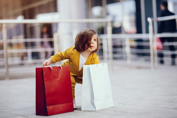 Beautiful girl in a summer city. Child with shopping bags