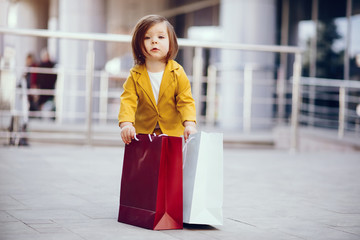 Beautiful girl in a summer city. Child with shopping bags