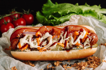 Hot dogs with ketchup, mustard and vegetables on wooden table