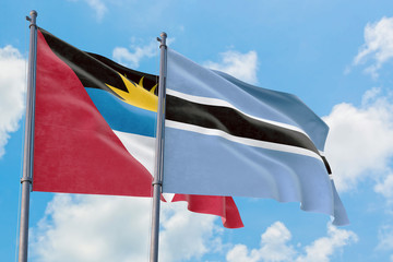 Botswana and Antigua and Barbuda flags waving in the wind against white cloudy blue sky together. Diplomacy concept, international relations.