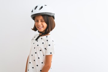 Beautiful child girl wearing security bike helmet standing over isolated white background winking looking at the camera with sexy expression, cheerful and happy face.