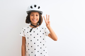 Beautiful child girl wearing security bike helmet standing over isolated white background showing and pointing up with fingers number three while smiling confident and happy.