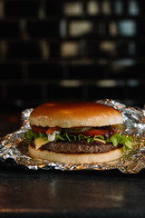 Tasty grilled homemade burger with beef, tomato, cheese, cucumber and lettuce. Delicious grilled burgers. Craft beef burger and french fries on wooden table