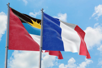 Fototapeta na wymiar France and Antigua and Barbuda flags waving in the wind against white cloudy blue sky together. Diplomacy concept, international relations.
