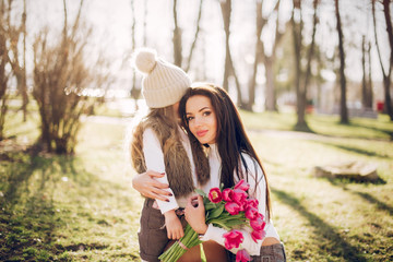 Fashionable mother with daughter. Family in a spring park. Mother's day