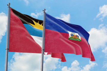 Haiti and Antigua and Barbuda flags waving in the wind against white cloudy blue sky together. Diplomacy concept, international relations.