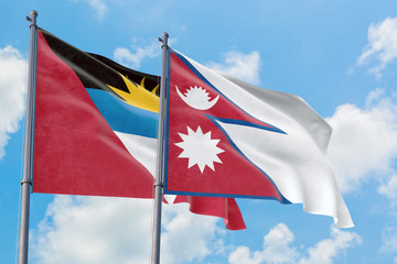 Nepal and Antigua and Barbuda flags waving in the wind against white cloudy blue sky together. Diplomacy concept, international relations.