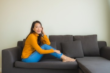 Portrait young asian woman happy relax smile on sofa chair with pillow in living room