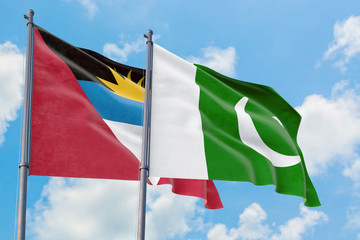Pakistan and Antigua and Barbuda flags waving in the wind against white cloudy blue sky together. Diplomacy concept, international relations.