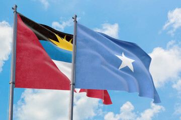 Somalia and Antigua and Barbuda flags waving in the wind against white cloudy blue sky together. Diplomacy concept, international relations.