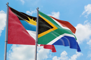 South Africa and Antigua and Barbuda flags waving in the wind against white cloudy blue sky together. Diplomacy concept, international relations.