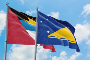 Tokelau and Antigua and Barbuda flags waving in the wind against white cloudy blue sky together. Diplomacy concept, international relations.