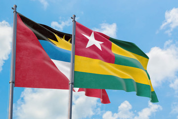 Togo and Antigua and Barbuda flags waving in the wind against white cloudy blue sky together. Diplomacy concept, international relations.
